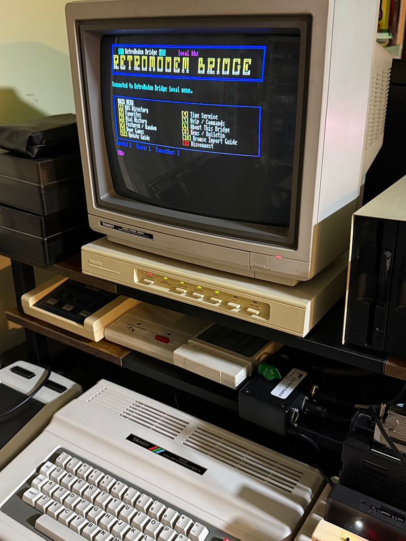 Tandy Color Computer 3 running GiME ANSi and connected through FujiNet to the RetroModem Bridge local BBS menu
